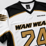 Custom lacrosse jersey close-up showing white gold black sublimated design and Wani Wear neck label