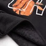 Close-up of reinforced shoulder stitching and ribbed cuff on a black basketball hoodie