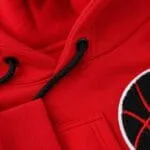 Close-up of black drawcords, metal eyelets, stitching, and basketball patch on a red hoodie