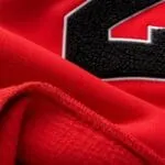 Close-up of soft red fleece fabric and black chenille number patch with embroidered border