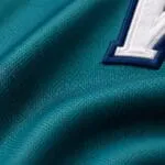 Breathable teal performance fabric and white tackle-twill lettering close-up