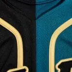 Teal and black baseball jersey fabric close-up with gold piping and embroidered lettering