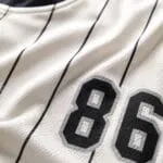 Custom baseball T-shirt fabric close-up showing breathable cream material, black pinstripes and number 86 print