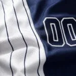 Breathable moisture-wicking polyester fabric close-up on a navy and white sublimated baseball jersey