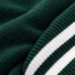Close-up of dark green varsity jacket fabric beside green and white striped rib knit trim