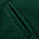 Close-up of slanted welt pocket on green varsity jacket with tonal edge stitching