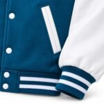 Close-up of textured blue body fabric beside a smooth white sleeve on a custom varsity jacket