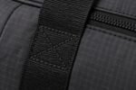 Close-up of box-X reinforced webbing handle stitching and matte black zipper on ripstop travel duffel