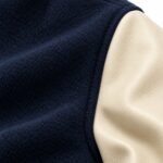 Close-up of textured navy body fabric joined to a cream pebbled-grain sleeve at the shoulder seam