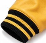 Black and gold striped rib-knit cuff on a gold leather sleeve of a custom letterman jacket