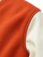 Close-up of orange wool body and white leather sleeve seam on a custom varsity jacket