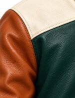 Leather grain and stitching detail where tan sleeve meets cream yoke and green body