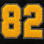 Close-up of gold chenille number with grey border on black wool varsity jacket
