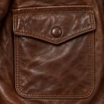 Snap-flap patch pocket with tonal stitching on brown leather aviator jacket