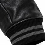Close-up of grained leather sleeve and black grey striped rib knit cuff on custom varsity jacket