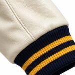 Close-up of cream pebble-grain leather sleeve with navy and gold striped rib knit cuff
