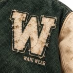 Close-up of cracked leather W letter patch with frayed edges on custom varsity jacket