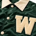 Close-up of chenille W letter patch and cream snap buttons on custom coach jacket