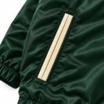 Close-up of piped welt pocket with cream trim on custom satin coach jacket