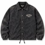 Front view of black acid wash custom coach jacket with snap-button closure, chest logo print and woven neck label