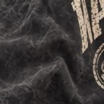 Close-up of vintage washed black cotton twill custom coach jacket with distressed cream screen print