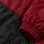 Close-up of crinkle nylon windbreaker fabric showing double-stitched panel seam and elastic cuff