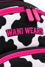 Close-up of pink arched Wani Wears embroidery with black outline and hot pink zipper pullers on cow print fabric