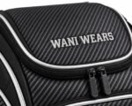 Close-up of embroidered Wani Wears logo on carbon texture bat backpack with silver piping and black zippers