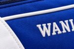 Close-up of white embroidered Wani Wears logo on blue polyester softball bag fabric