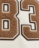 Close-up of tan chenille number patch with brown and cream borders on wool varsity jacket